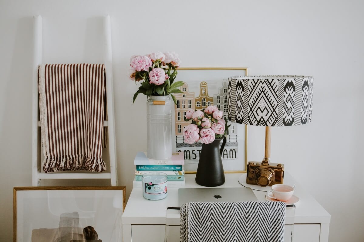 Coin bureau décoré avec des fleurs roses, une lampe à motifs noirs et blancs et des accessoires décoratifs.